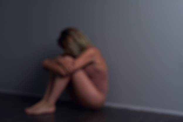 A blurred image depicts a person hunched against a gray wall, likely conveying distress. This visually supports the surrounding content addressing sensitive issues related to website content removal.